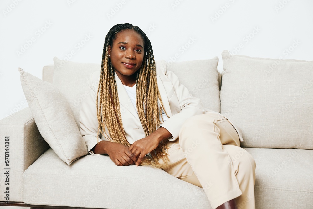 Happy african american woman sitting at home on sofa, rest and vacation smile, light background. Relaxed home lifestyle, day off. Happy african american woman sitting at home on sofa, rest and vacation smile, light background. Relaxed home lifestyle, day off.