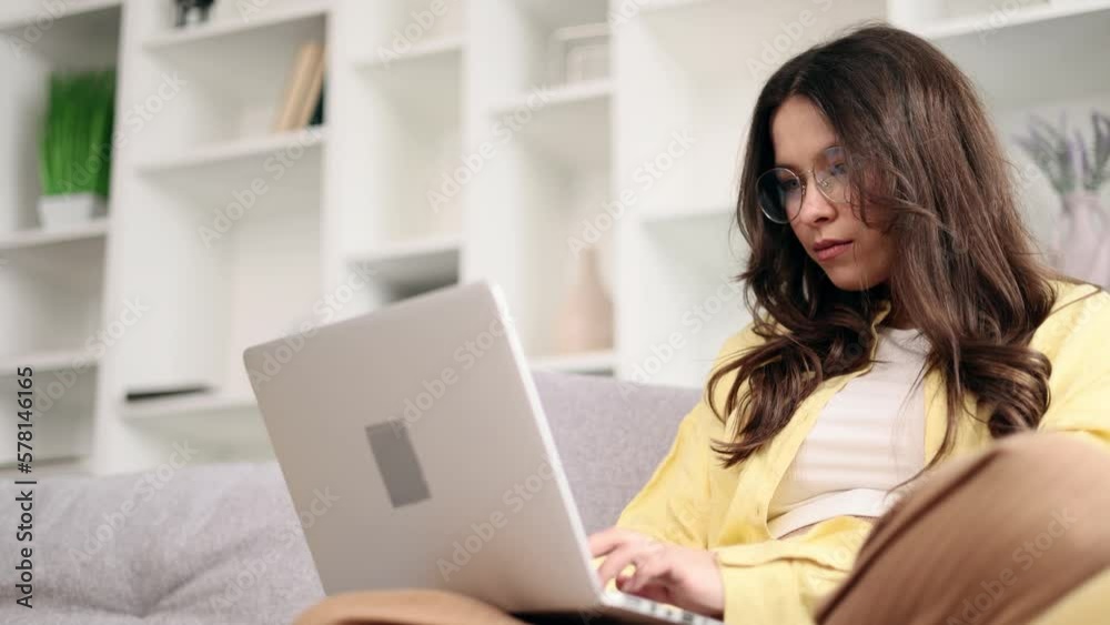 Portrait of young caucasian woman relaxing at home or working online typing browsing products in internet store reading news checking email or social media profile on laptop computer indoors Portrait of young caucasian woman relaxing at home or working online typing browsing products in internet store reading news checking email or social media profile on laptop computer indoors