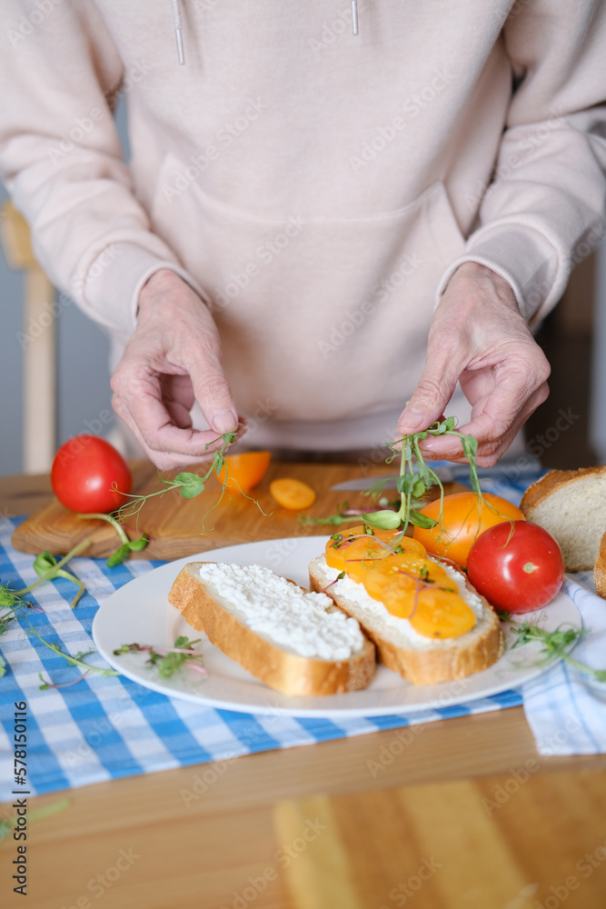 Age woman preparing healthy sandwiches with microgreens and vegetables