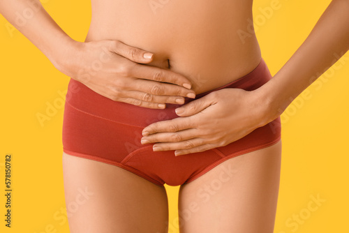 Young woman in menstrual panties on yellow background, closeup