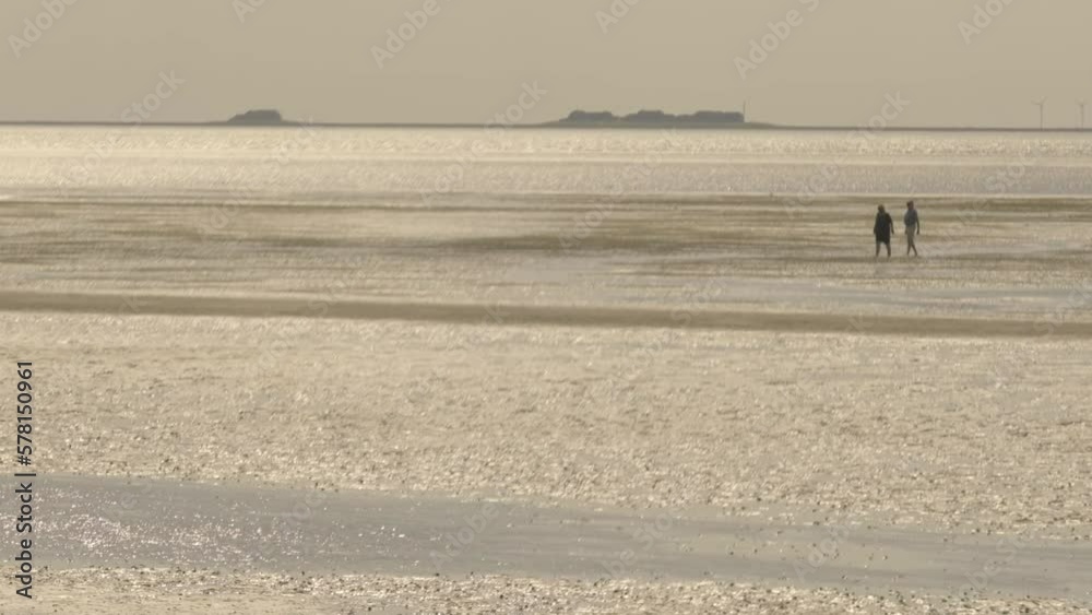 Wadden Sea.walking on watt dunes. Silhouettes of people on the beach.Walks along the sandy bottom of the wattled North Sea of Germany.Fer Island.Recreation and vacation at sea. Wadden Sea.walking on watt dunes. Silhouettes of people on the beach.Walks along the sandy bottom of the wattled North Sea of Germany.Fer Island.Recreation and vacation at sea.
