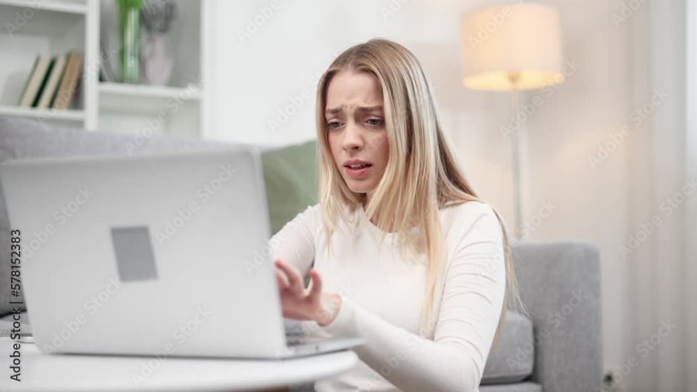 Nervous stressed young blond woman freelancer typing quickly on laptop computer and looking at screen ignoring phone ring asking to hurry up and worrying about deadline at home Nervous stressed young blond woman freelancer typing quickly on laptop computer and looking at screen ignoring phone ring asking to hurry up and worrying about deadline at home