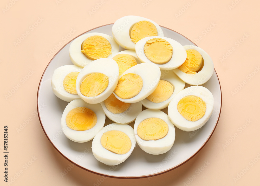 Plate with halves of delicious boiled eggs on beige background Plate with halves of delicious boiled eggs on beige background