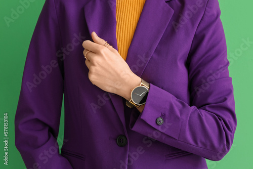 Woman with stylish wristwatch on green background, closeup