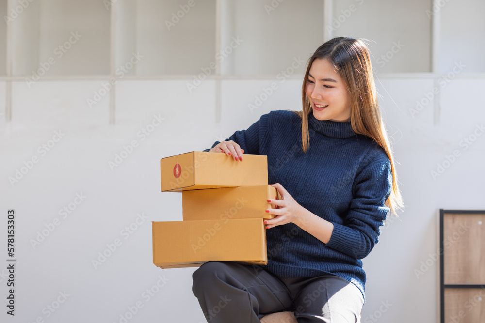 Startup small business entrepreneur of freelance Asian woman using a phone with box Cheerful success Asian woman her hand lifts up online marketing packaging box and delivery SME idea concept Startup small business entrepreneur of freelance Asian woman using a phone with box Cheerful success Asian woman her hand lifts up online marketing packaging box and delivery SME idea concept