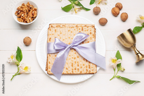 Composition with flatbread matza, walnuts and alstroemeria flowers on light wooden background