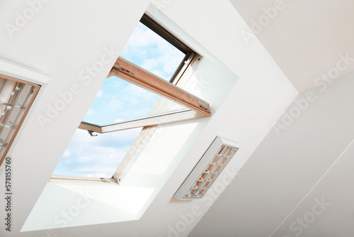 Tableau sur toile Open skylight roof window on slanted ceiling in attic room, low angle view