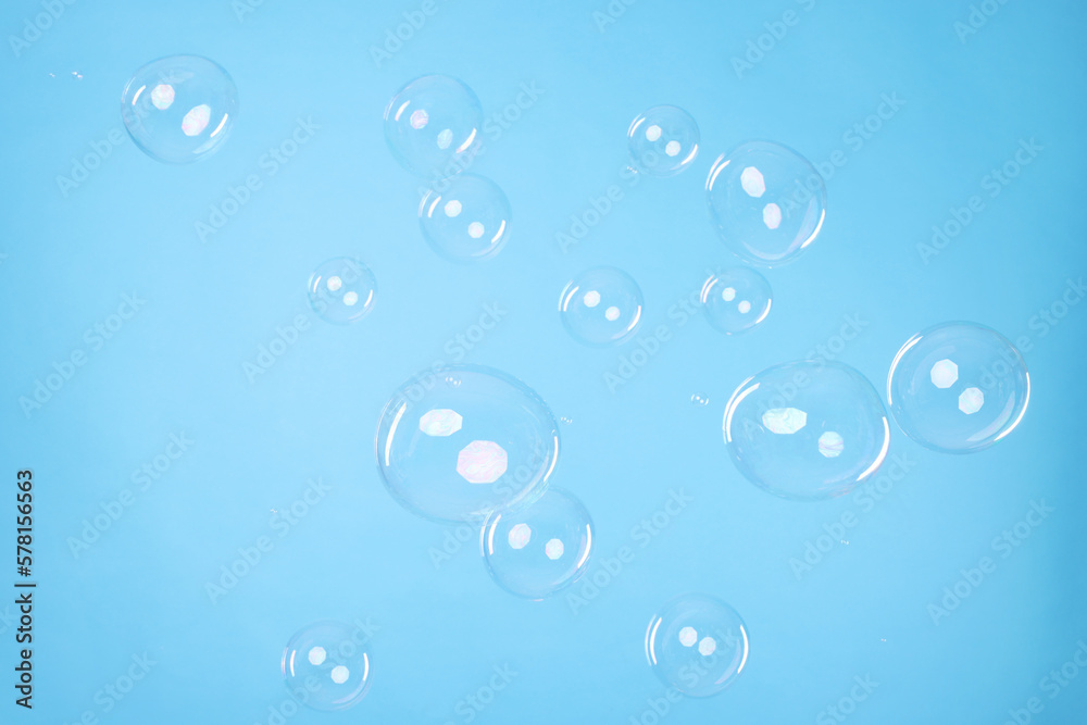 Many beautiful soap bubbles on light blue background