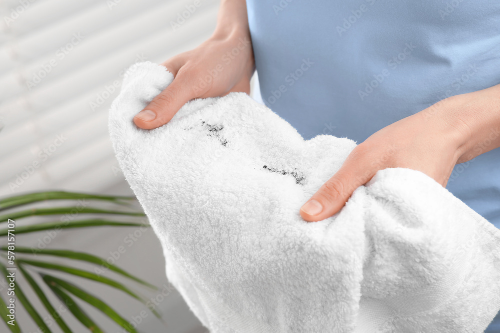 Woman holding terry towel with mascara spot indoors, closeup. Makeup removal Woman holding terry towel with mascara spot indoors, closeup. Makeup removal