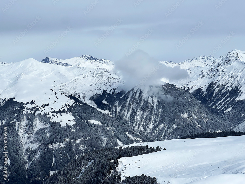 Obraz premium Beautiful sunlit and snow-capped alpine peaks above the Swiss tourist sports-recreational winter resort of Arosa - Canton of Grisons, Switzerland (Schweiz)