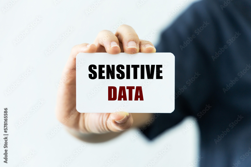 Sensitive data text on blank business card being held by a woman's hand with blurred background. Business concept about data privacy. Sensitive data text on blank business card being held by a woman's hand with blurred background. Business concept about data privacy.