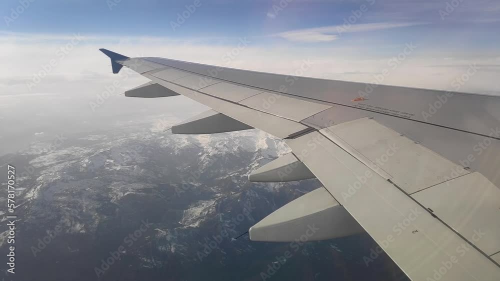 The wing of a passenger plane in flight. Passenger plane flying above the clouds. Airplane wing shot from the inside The wing of a passenger plane in flight. Passenger plane flying above the clouds. Airplane wing shot from the inside
