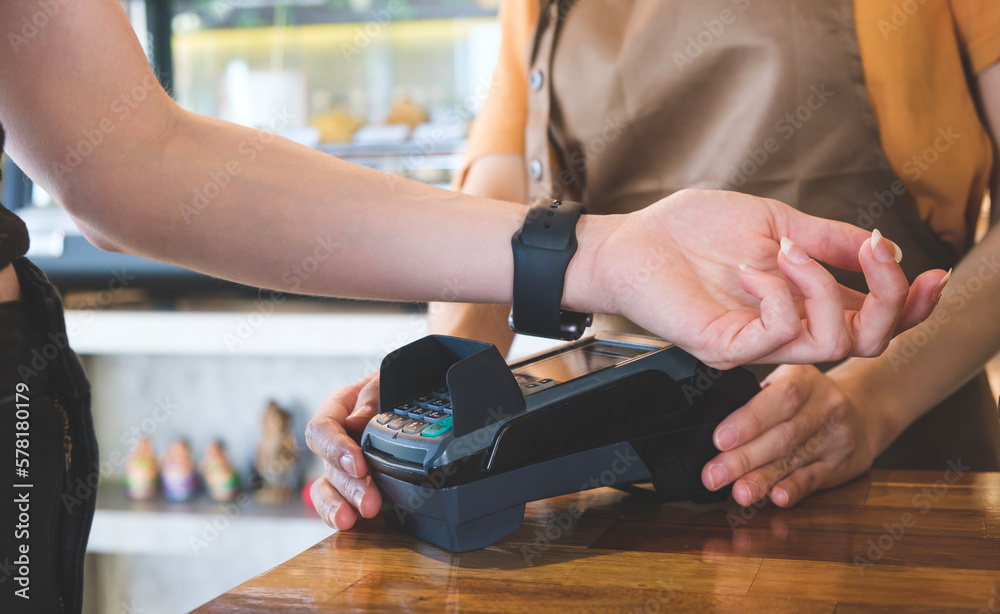 Female customer using smartwatch for contactless payment for her order in cafe. Non-cash payment concept. - obrazy, fototapety, plakaty 