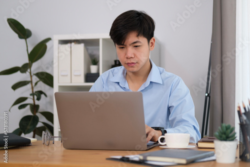 Smiling handsome asian man freelancer working with laptop computer..