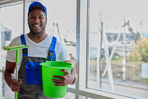 Foto Perfectly washed window sparkles in sun, dark-skinned cleaner is happy with job done