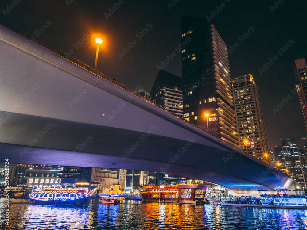 Dubai Marina, harbour, cruise boat and canal promenade view at night, in Dubai, United Arab Emirates