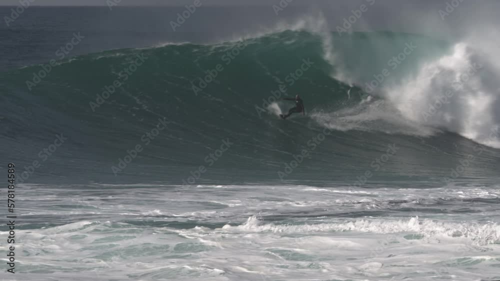 Surfer skillfully zigzags on a big wave that breaks behind him and ends his ride with a backflip Surfer skillfully zigzags on a big wave that breaks behind him and ends his ride with a backflip