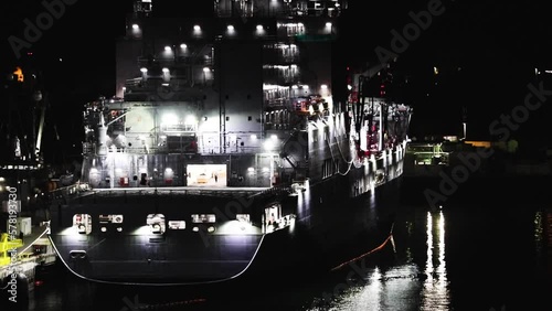 a navy ship tied up to a dock in the dark photo