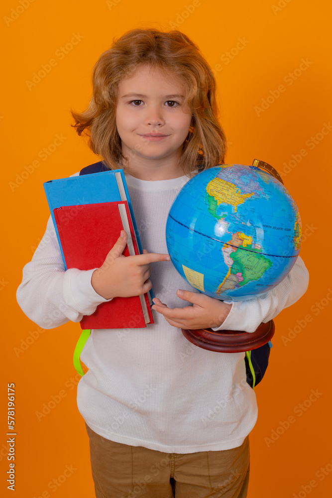 Fototapeta premium School children. School kid hold world globe and book. Back to school. Funny little student boy from elementary school with book. Pupil on studio isolated background.