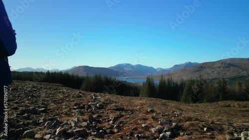 Fly past hiker overlooking Loch Loyne and pine forest in Scottish Highlands photo