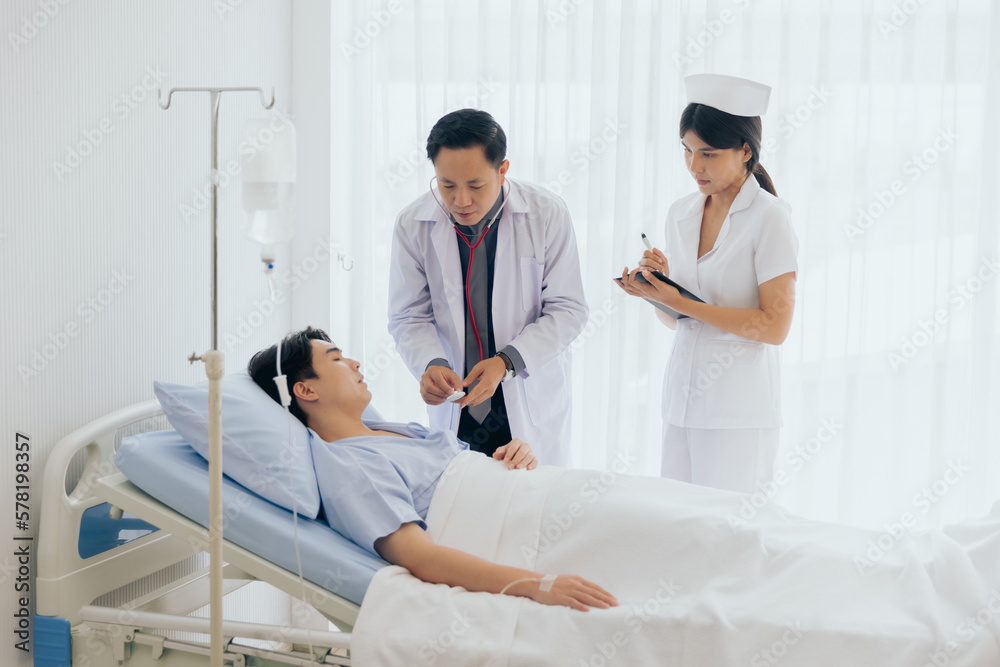 Doctor and nurse visiting and using stethoscope checking examine heartbeat male patient at hospital Doctor and nurse visiting and using stethoscope checking examine heartbeat male patient at hospital