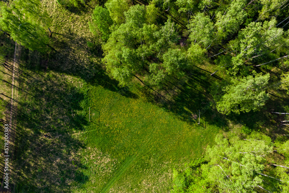 Beautiful green forest with an amateur football field, view from a great height Beautiful green forest with an amateur football field, view from a great height