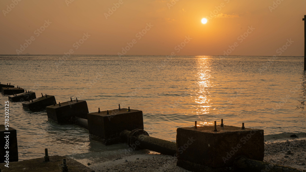 Sunset on a beach island with deck stones in line with orange hues and a tranquil feeling