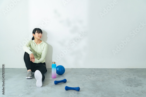 座る女性とトレーニング用品 フィットネスジム エクササイズ
