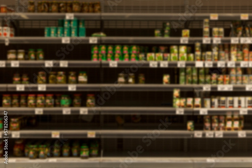 Half-empty shelves with canned food in the store. Panic and crisis. Blurred. Front view.