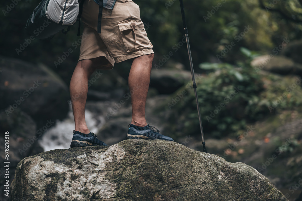 Hikers use trekking pole with backpacks walking through the rock and water on stream in the forest. hiking and adventure concept.