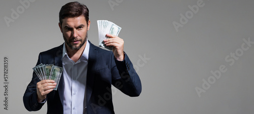 Portrait business man holding cash dollar bills over gray background. Big luck, banner. Dollar cash money concept. Rejoices to win cash. Man hold cash money. Financial luck and success.