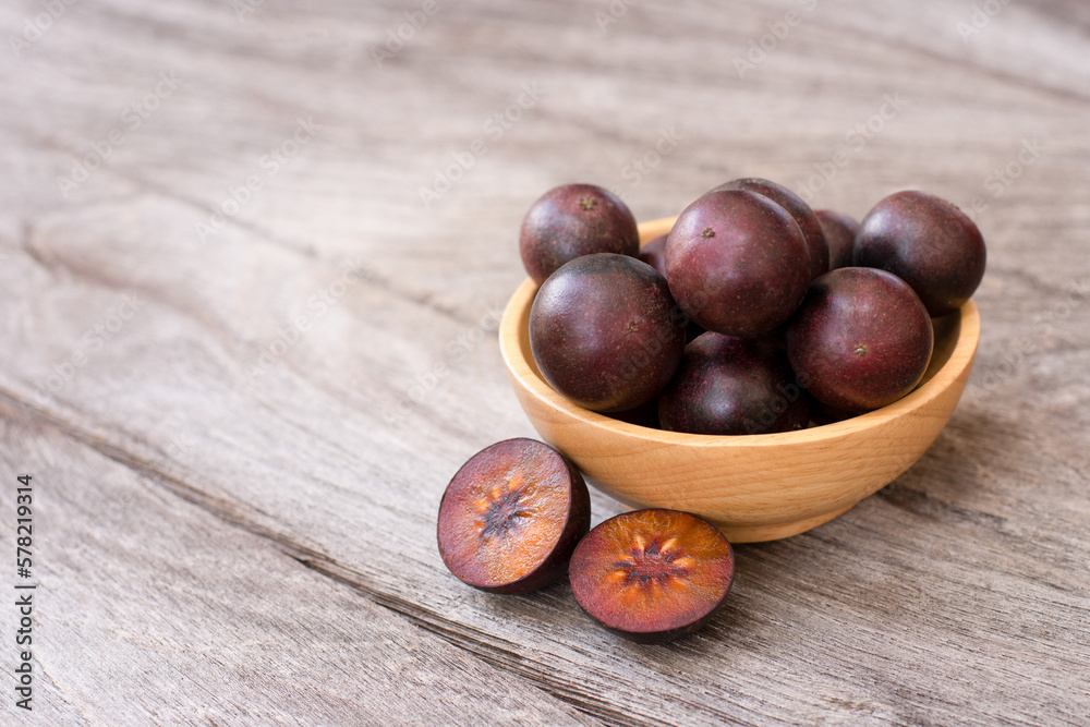 Flacourtia indica fruit with half sliced isolated on wooden table background.