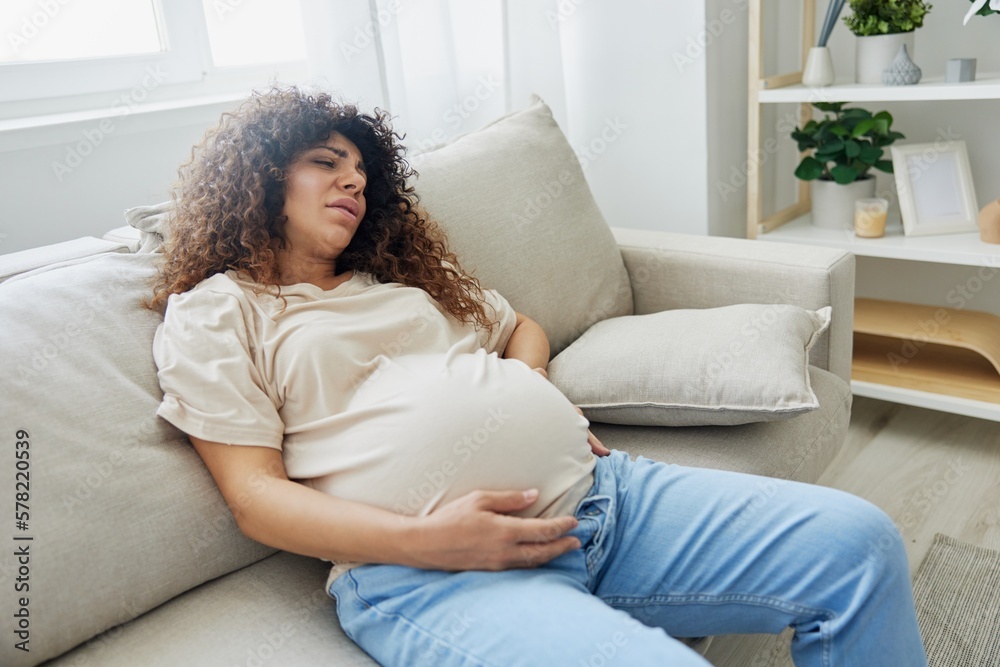 Pregnant woman lies on the couch at home headache, pregnancy and motherhood difficulties, severe fatigue, headache Pregnant woman lies on the couch at home headache, pregnancy and motherhood difficulties, severe fatigue, headache