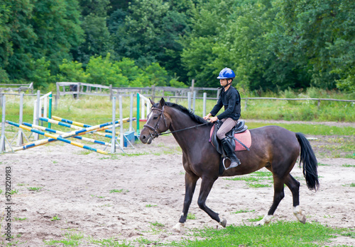 Boy and horse. Horseback Riding. Jumping. Sportsman boy on a brown horse breaks a barrier © Irina Ukrainets