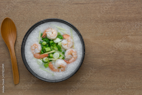 top view of rice porridge with shrimp in a ceramic bowl on wooden table. asian homemade style food concept.