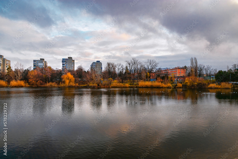 Obraz premium Modern buildings near the lake. City buildings near the lake. Residential buildings near the lake, surrounded by yellow trees. Multi-storey modern residential buildings near the pond in autumn color.