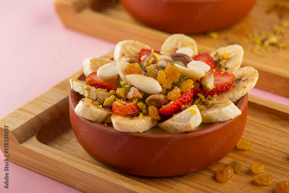 Mohalabiya with banana, strawberry, nut, raisin, and honey closeup shot 