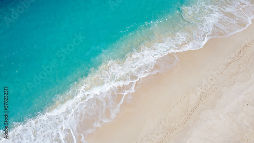 Aerial drone of whitewash waves rolling and crashing onto white sandy beach coastline from pristine turquoise ocean water on tropical island