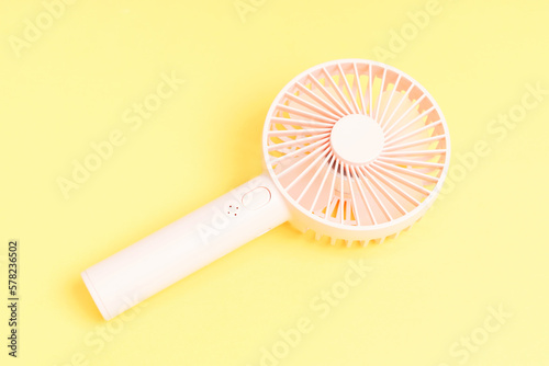 Small portable fan on yellow background close-up, copy space.