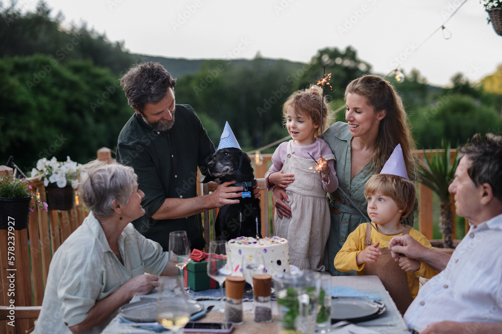 Fototapeta premium Multi generation family celebrating birthday of their dog and having garden party outside on patio.