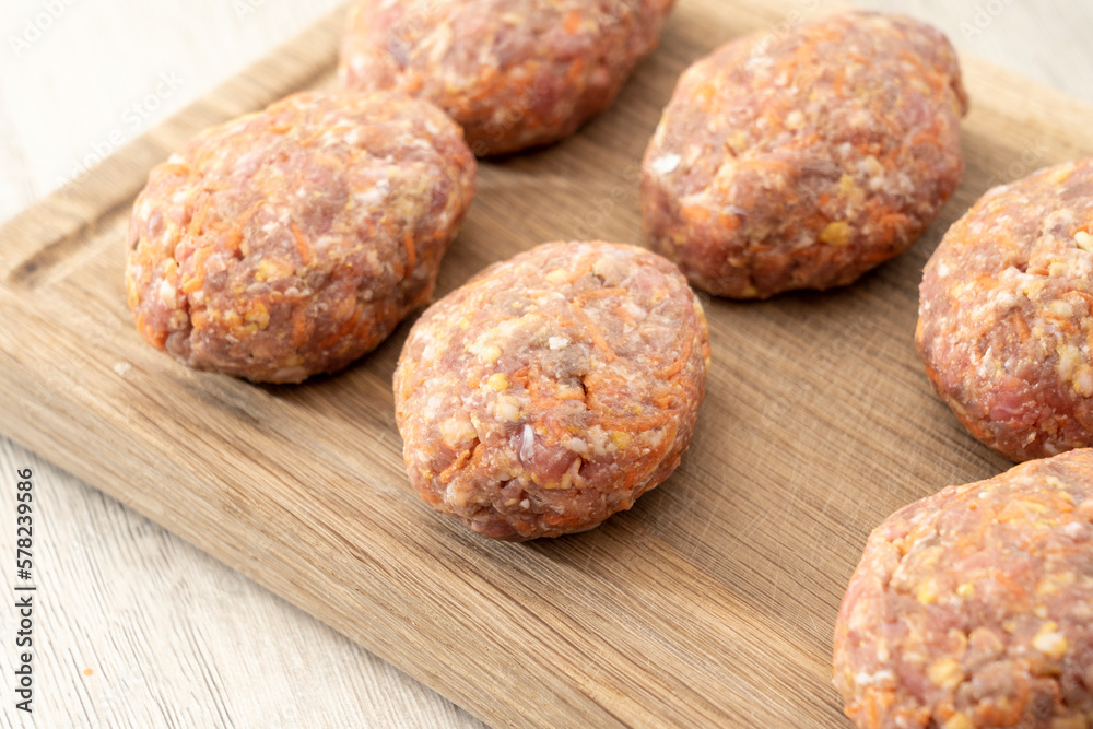raw homemade meatballs on a massive board made of natural wood raw homemade meatballs on a massive board made of natural wood