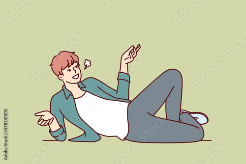 Serene man lies on floor and smiles talking about plans for future or telling interesting humorous stories. Serene guy looks up spreading arms resting on ground after hard day at work