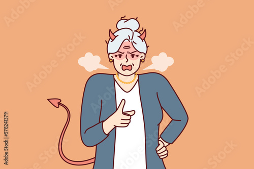 Elderly woman with horns and devil tail screams and points with finger, scolding and threatening opponent. Gray-haired woman pensioner in image of devil feels hatred for concept of senile aggression