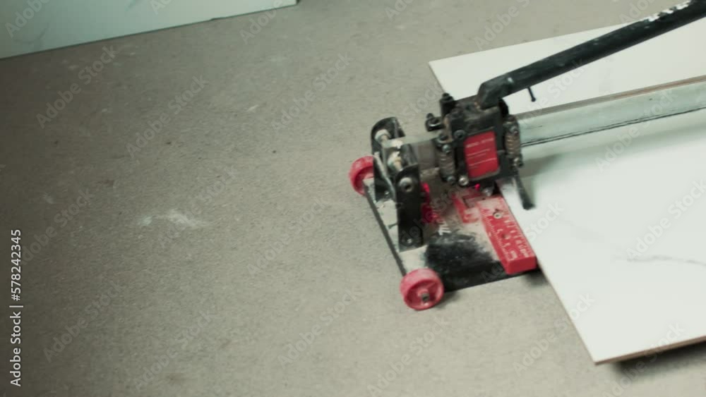 Person cutting a tile on a tile cutter. Renovating a house. Men at work. Person cutting a tile on a tile cutter. Renovating a house. Men at work.