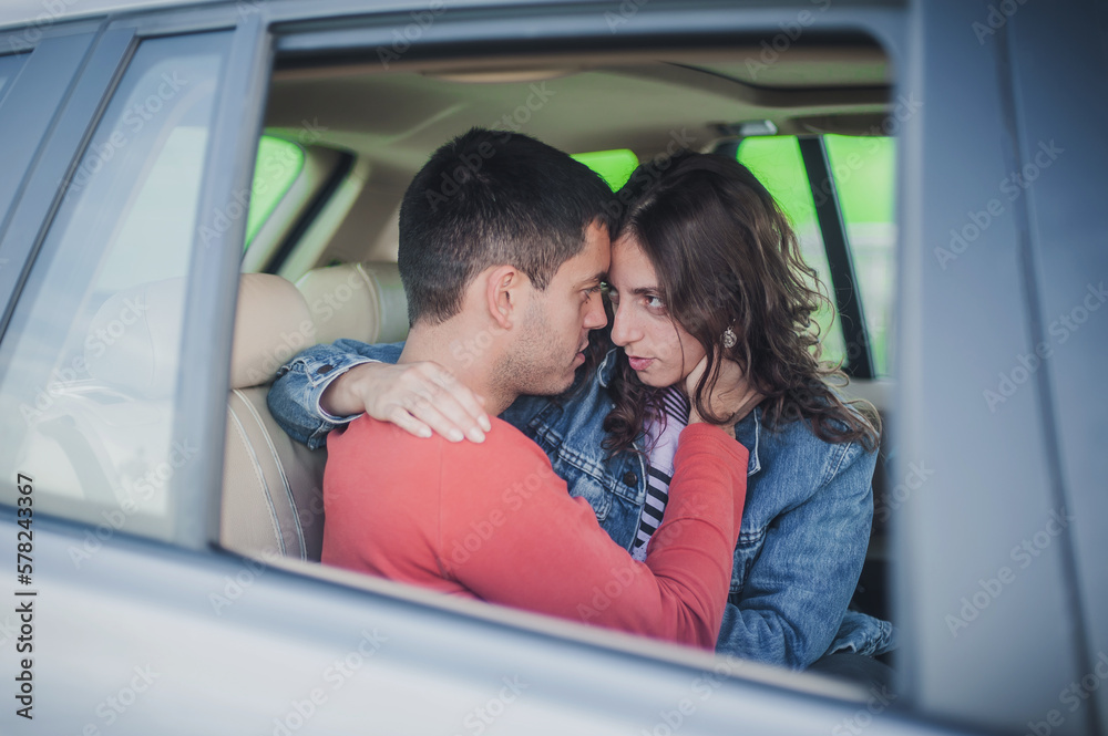 Passionate kiss in car. View through the window. Young sexy couple in love, sitting in the back seat, looking and kissing passionately each other, just before sex. Desire, passion and love concept Passionate kiss in car. View through the window. Young sexy couple in love, sitting in the back seat, looking and kissing passionately each other, just before sex. Desire, passion and love concept