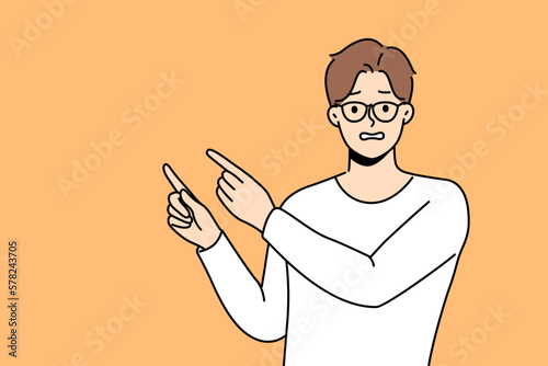 Frustrated man point with finger at empty advertising space. Confused unhappy guy recommend deal or offer feel awkward. Vector illustration. 