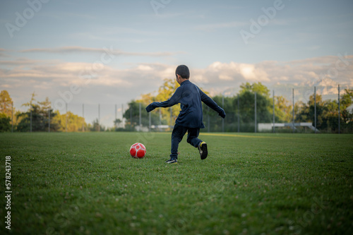 Child playing football. One Asian boy kicking ssoccer.