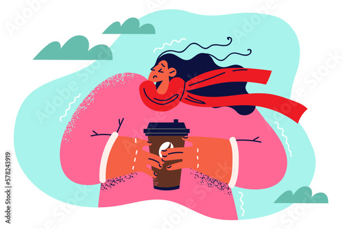 Frozen woman from plastic cup coffee stands on street and drinks hot drink to warm herself