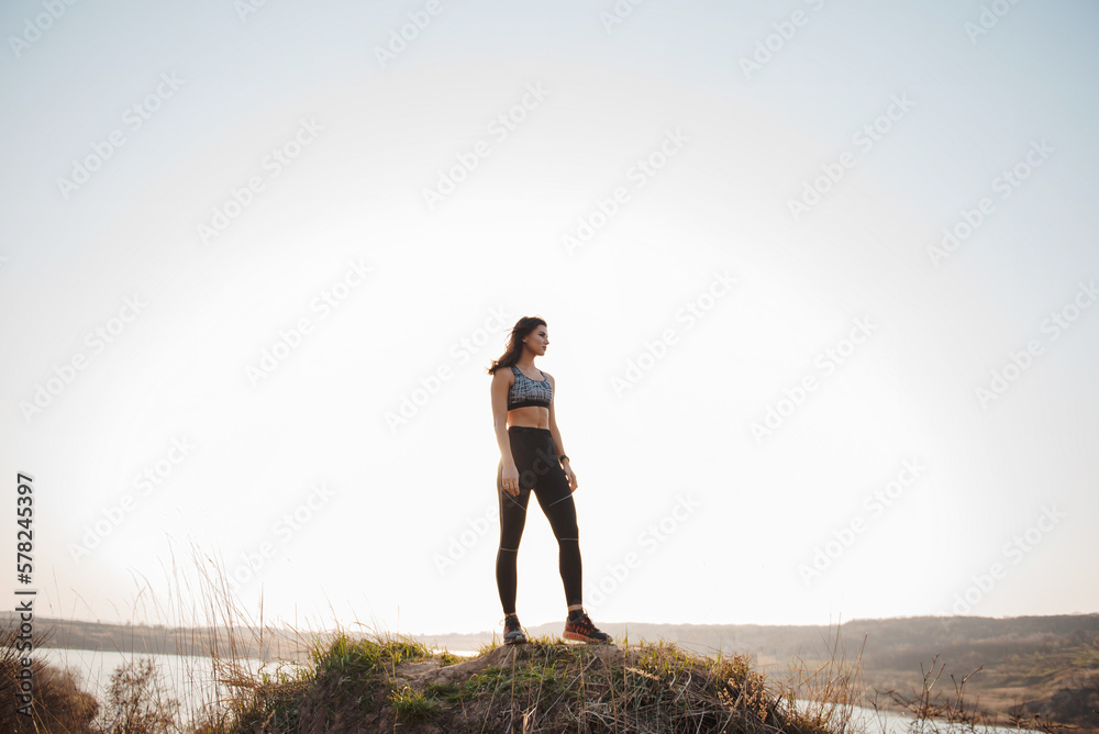 Young woman with athletic body shape standing on high hill Young woman with athletic body shape standing on high hill