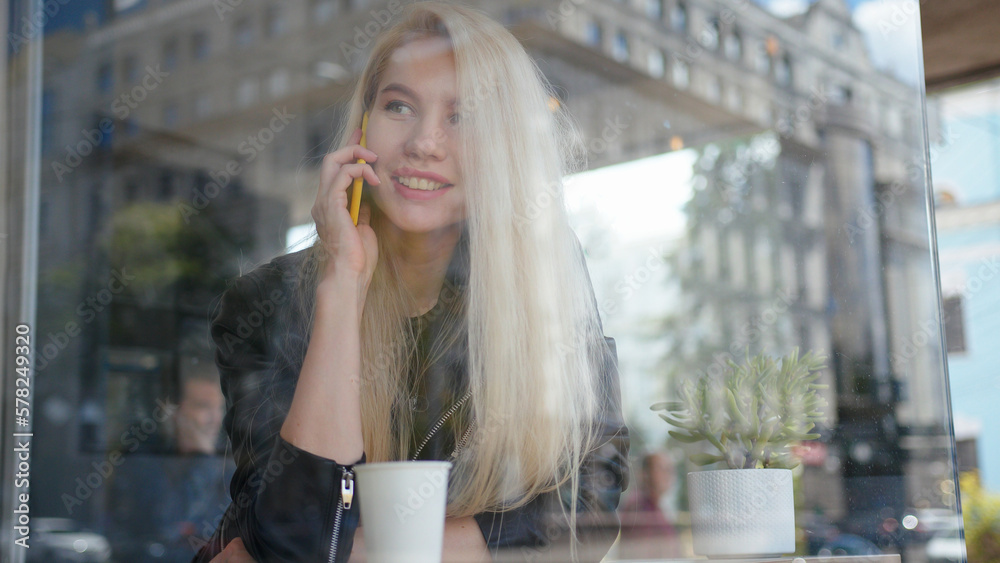 Fototapeta premium Mixed race smiling woman sitting in a cafe and talking on the phone